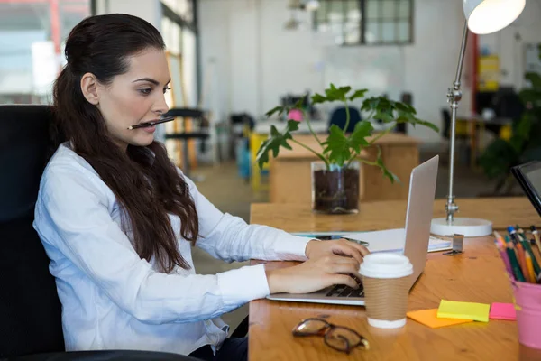 Female business executive using laptop at desk — Stock Photo, Image