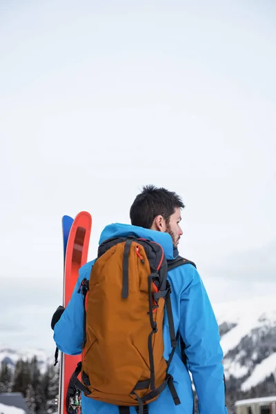 Скіпер стоїть з лижами на засніжених горах — стокове фото