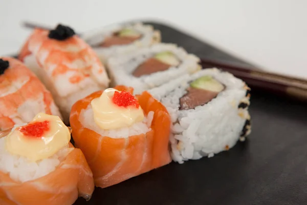 Uramaki e nigiri sushi servido com pauzinhos em ardósia de pedra preta — Fotografia de Stock