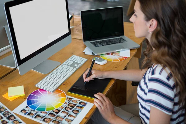 Designer gráfico feminino usando tablet gráficos na mesa — Fotografia de Stock