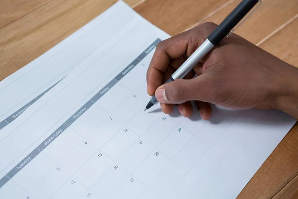 Geschäftsmann markiert mit Stift auf Kalender — Stockfoto