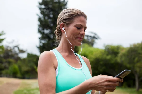 Atleta femenina escuchando música en el teléfono móvil — Foto de Stock