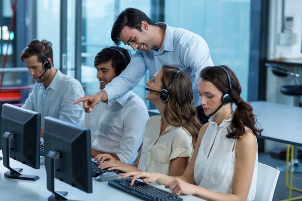 Bedrijfsleiders met headsets met behulp van computer — Stockfoto