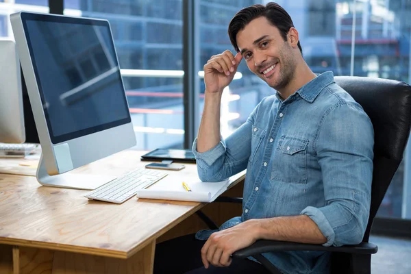 Hombre feliz sentado en el escritorio en la oficina — Foto de Stock