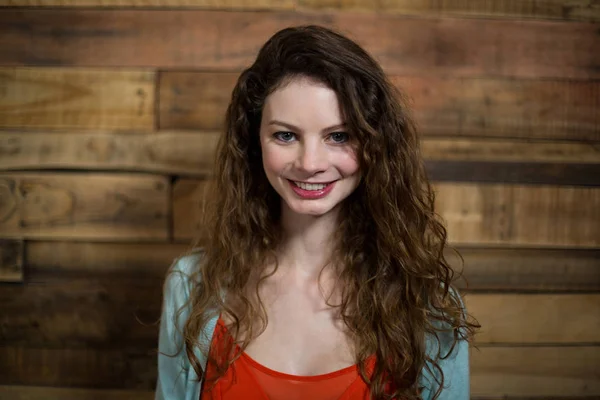 Retrato de mulher sorridente em pé contra a parede de madeira — Fotografia de Stock