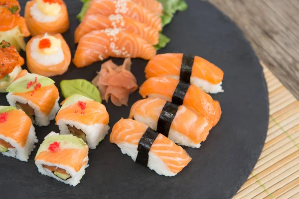 Plateau d'ardoise de sushis assortis conservés sur le tapis — Photo