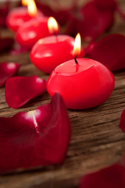 Röd vaxljus med rosenblad — Stockfoto