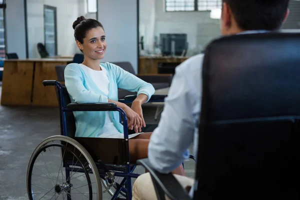 İş kadını ofiste iş arkadaşı ile konuşurken tekerlekli sandalyede — Stok fotoğraf