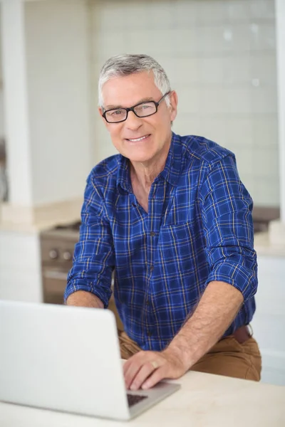 Retrato de homem sênior usando laptop na cozinha — Fotografia de Stock