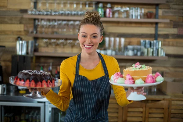 Portrait of waitress holding a plate of cake — Stock Photo, Image