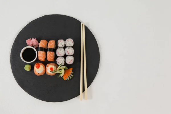 Uppsättning av blandade sushi serveras på svart sten skiffer med ätpinnar och sojasås — Stockfoto