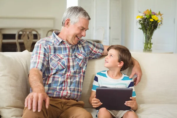 Avô com seu neto usando tablet digital no sofá — Fotografia de Stock