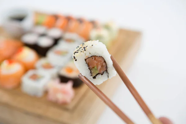 Uramaki sushi som hålls i trä ätpinnar — Stockfoto