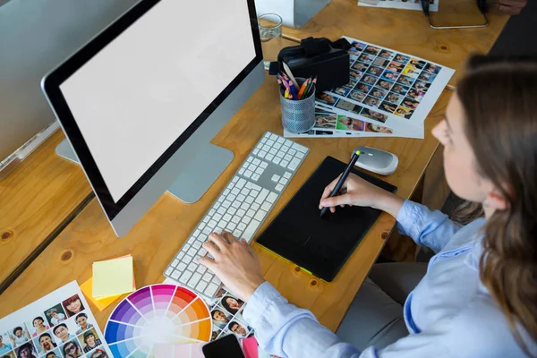 Жіночий графічний дизайнер, використовуючи графічний планшет за столом — стокове фото