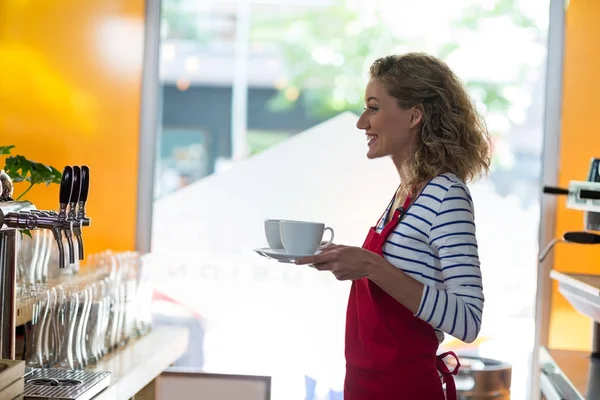 Портрет улыбающейся официантки, стоящей с чашкой кофе — стоковое фото