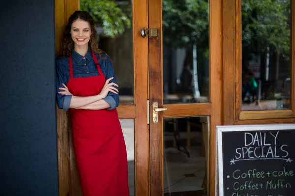 Portrait of smiling waitress standing with arms crossed — Stock Photo, Image