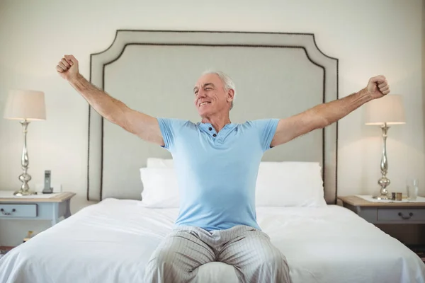 Homem sênior esticando os braços na cama — Fotografia de Stock