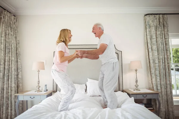 ベッドの上で踊って幸せな先輩カップル — ストック写真
