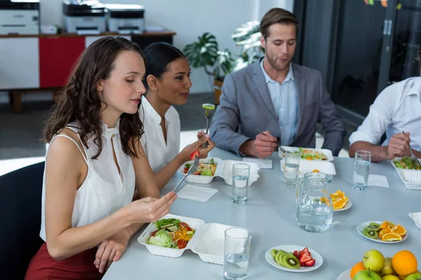 Glimlachende zakenmensen met maaltijd in kantoor — Stockfoto