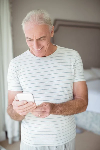 Gelukkig senior man gebruik mobiele telefoon in de slaapkamer — Stockfoto