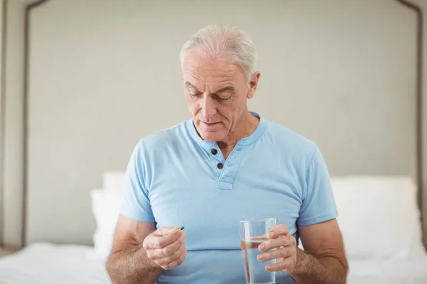 Senior man met geneeskunde en glas water — Stockfoto