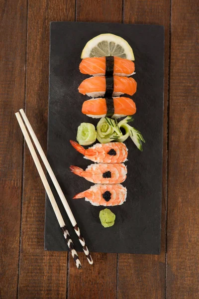 Nigiri sushi serveras med ätpinnar i svart sten skiffer — Stockfoto