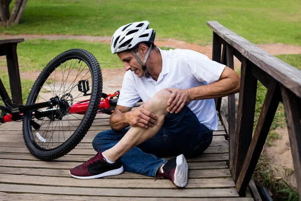 Cycliste tombé tenant son genou blessé — Photo