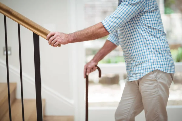 Senior man climbing upstairs with walking stick — Stock Photo, Image