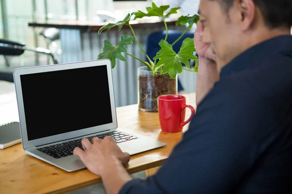 Бизнес-руководитель сидит за столом и использует ноутбук — стоковое фото