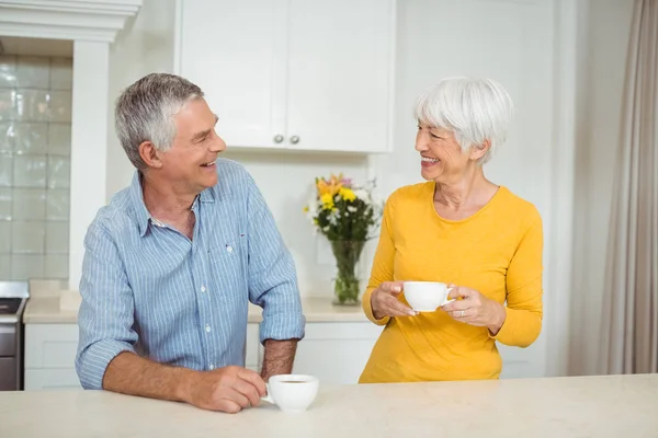 Счастливая пожилая пара пьет кофе на кухне — стоковое фото