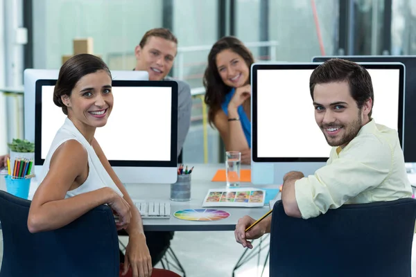 Portrait of smiling graphic designers sitting at desk — Stock Photo, Image