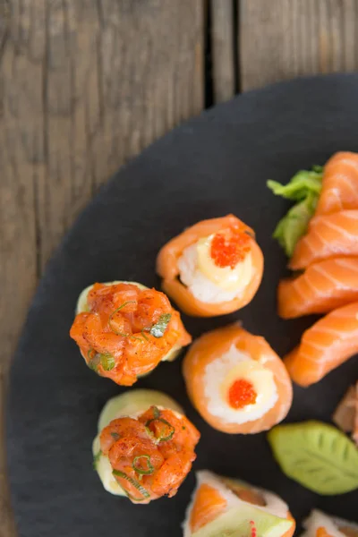 Set of assorted sushi served on black stone slate — Stock Photo, Image