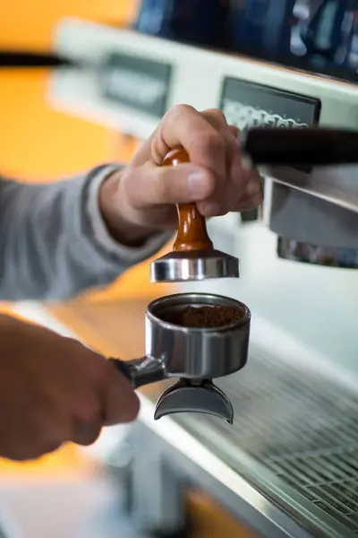 Camarero usando un manipulador para presionar el café molido en un portafilter —  Fotos de Stock