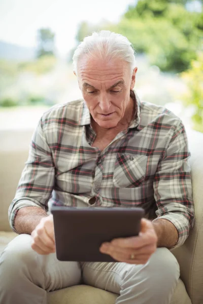 Старший мужчина с помощью цифрового планшета в гостиной — стоковое фото