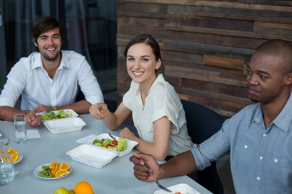 Smiling business executive having meal in office — Stock Photo, Image