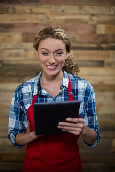 Porträt einer lächelnden Kellnerin mit digitalem Tablet gegen Holzwand — Stockfoto