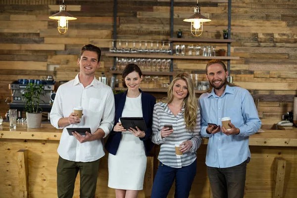 Jóvenes amigos usando tableta digital y teléfono móvil mientras toman café — Foto de Stock