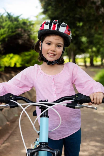 Portret van lachende meisje permanent met fiets in park — Stockfoto