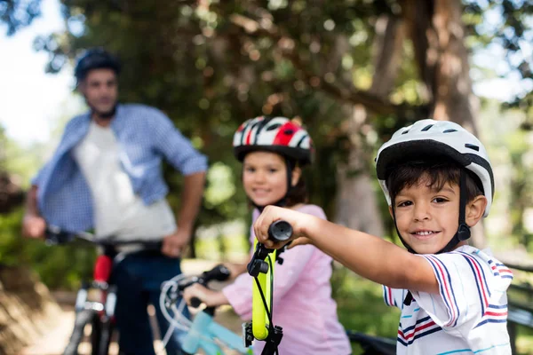 Father and children standing with bicycle in park — Stock Photo, Image