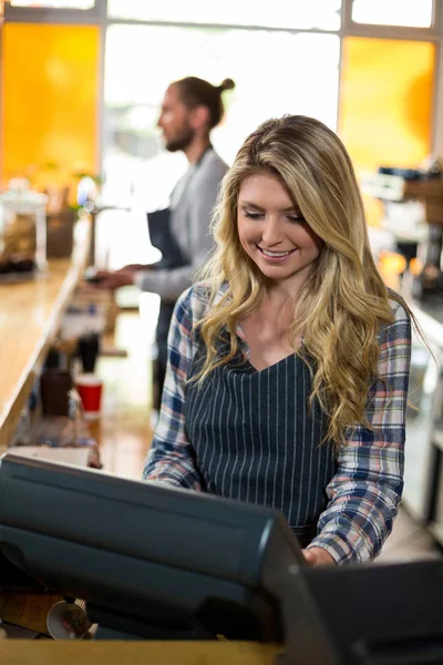 Lächelnde Kellnerin arbeitet am Computer am Schalter — Stockfoto