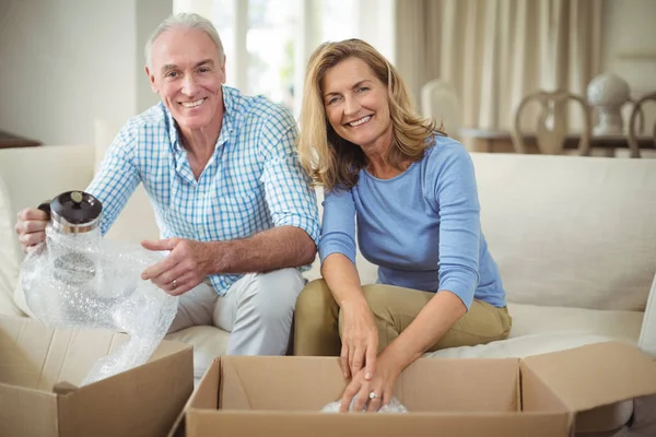 Sorrindo casal sênior desembalar caixas de papelão na sala de estar — Fotografia de Stock