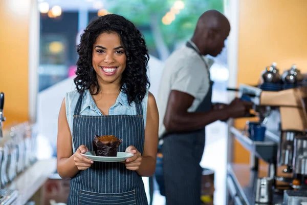 Portrait of smiling waitress holding a plate of cupcake — Stock Photo, Image