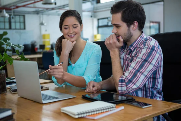 Smiling business executives discussing over laptop — Stock Photo, Image