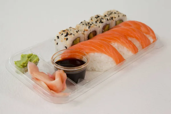 Nigiri en uramaki geserveerd met sojasaus in plastic doos — Stockfoto