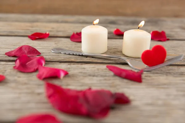Brennende Kerzen umgeben von aromatischen Rosenblättern — Stockfoto