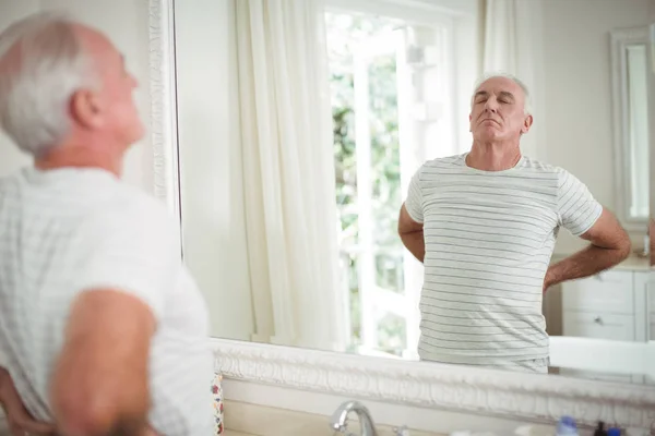 Старший мужчина растягивается перед зеркалом — стоковое фото