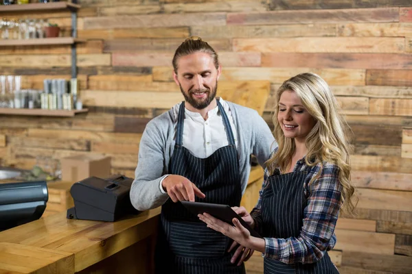 Улыбающийся официант и официантка с цифровым планшетом за прилавком — стоковое фото