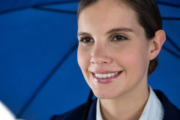 Femme d'affaires souriante tenant parapluie bleu — Photo