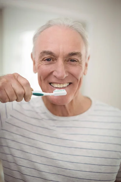 Portret van senior man houden tandenborstel in de badkamer — Stockfoto