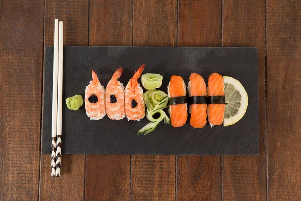 Sushi nigiri servido con palillos en pizarra de piedra negra —  Fotos de Stock